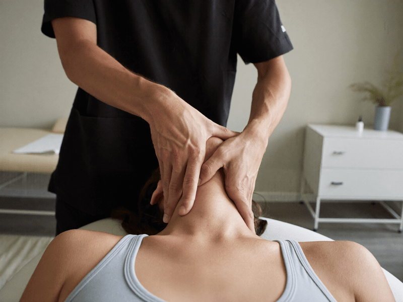 Ost&eacute;opathe posant d&eacute;licatement les mains sur la nuque d'un patient allong&eacute;, technique tissulaire douce