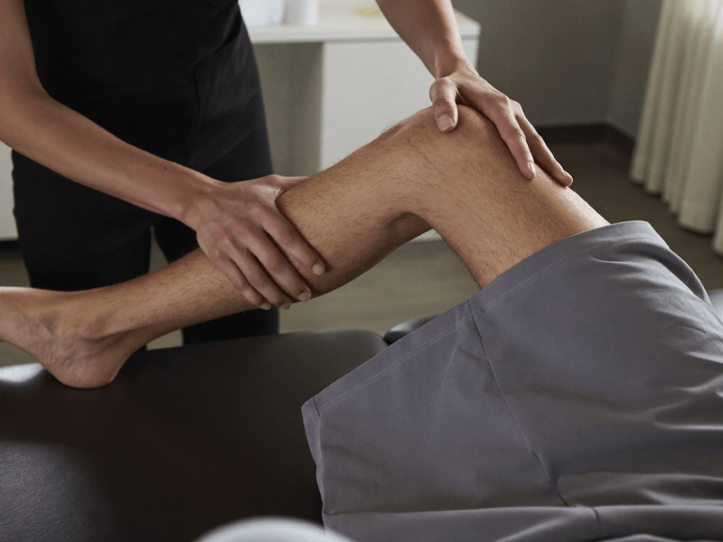 Kin&eacute;sith&eacute;rapeute testant la mobilit&eacute; du genou d'un patient, comparaison entre f&eacute;mur et tibia