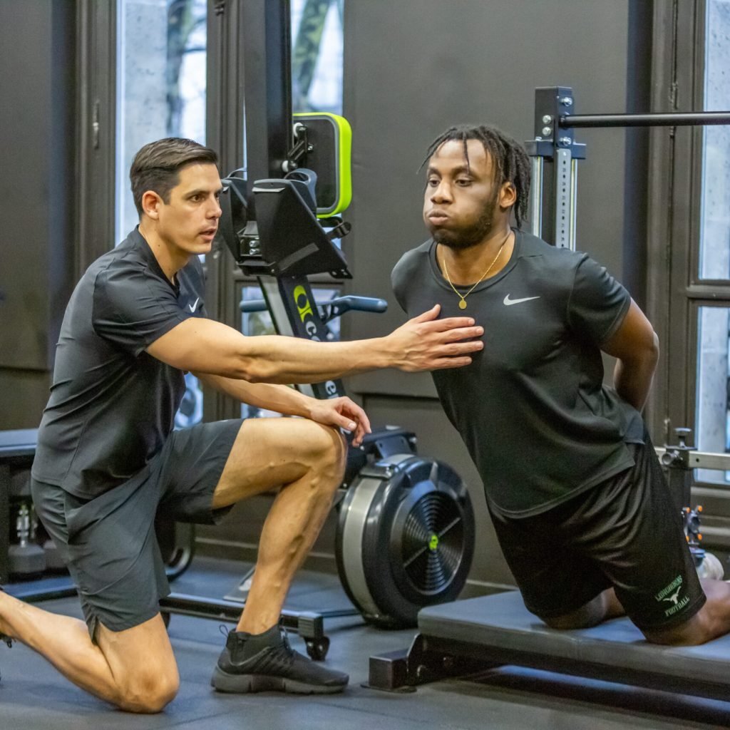Thibault Vignais, kin&eacute;sith&eacute;rapeute du sport, encadrant un athl&egrave;te lors d&rsquo;un exercice de mobilit&eacute; et de renforcement fonctionnel en salle